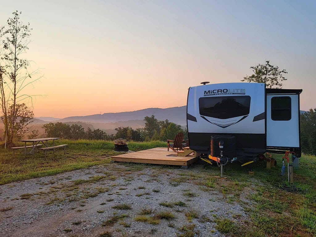 An RV parked in a field at sunset, surrounded by blooming flowers.