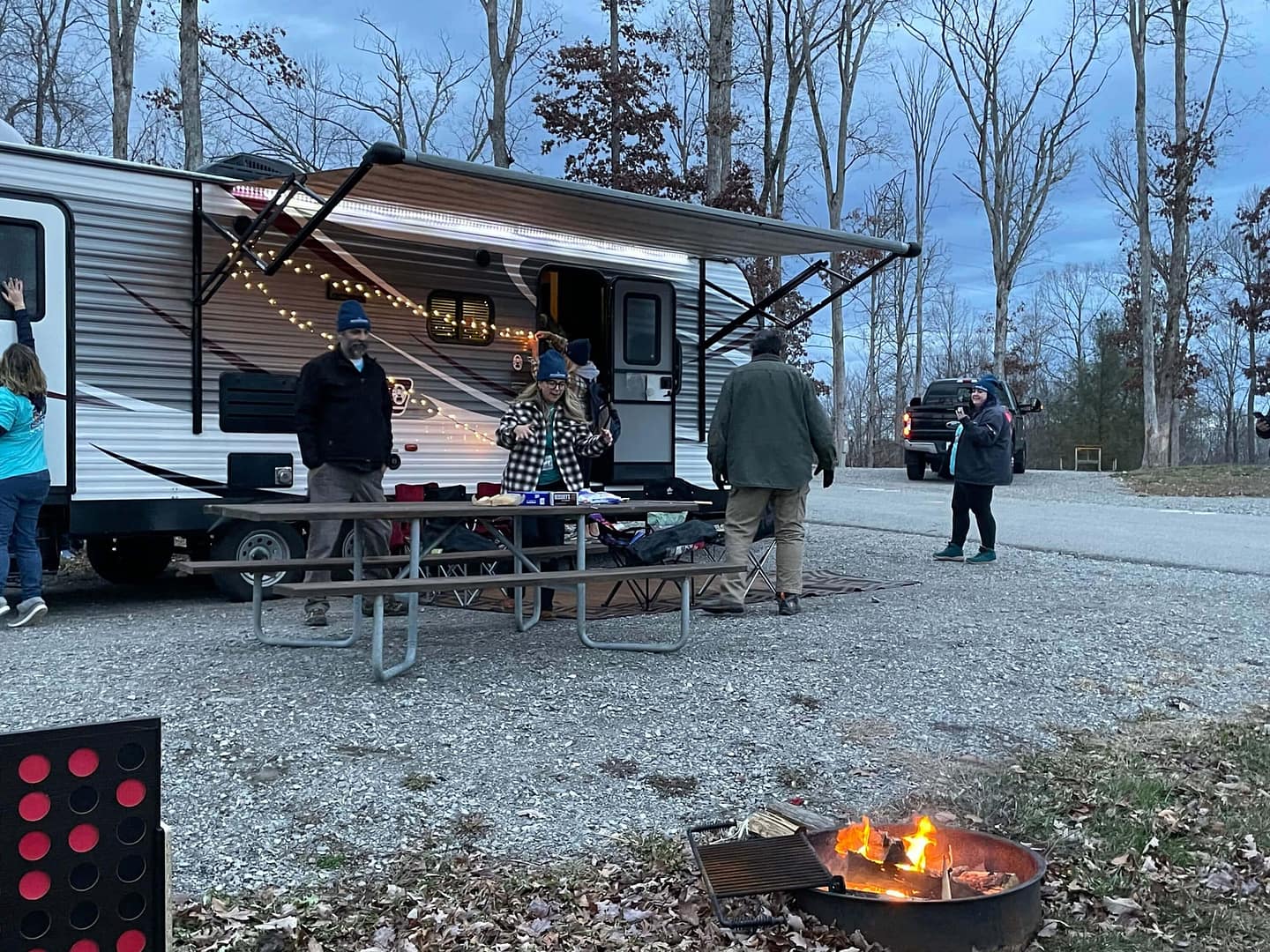 A group of people standing around a campfire near an RV in the Southeastern United States, enjoying the Magic of Christmas.