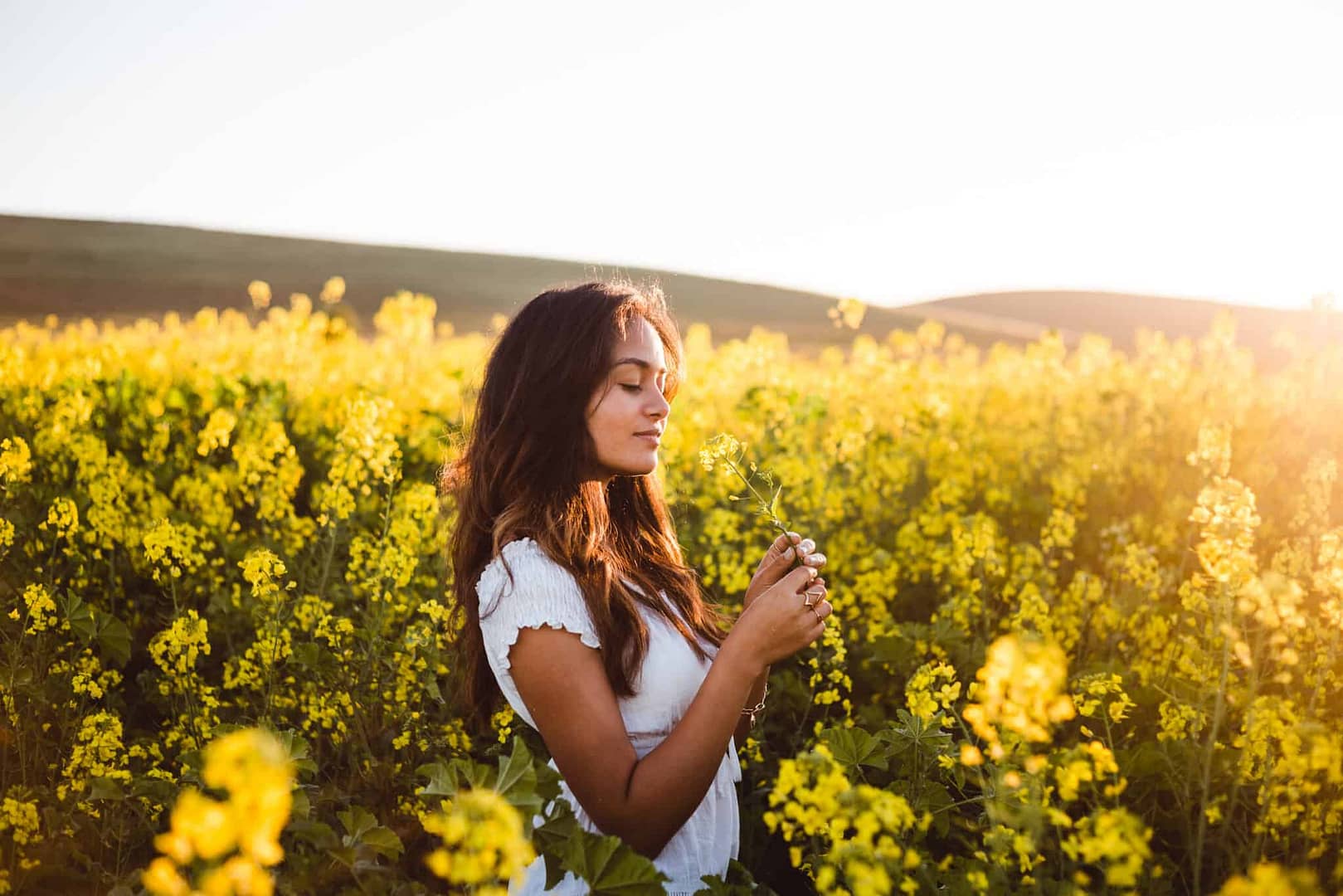 A young woman in a field of blooming yellow flowers.