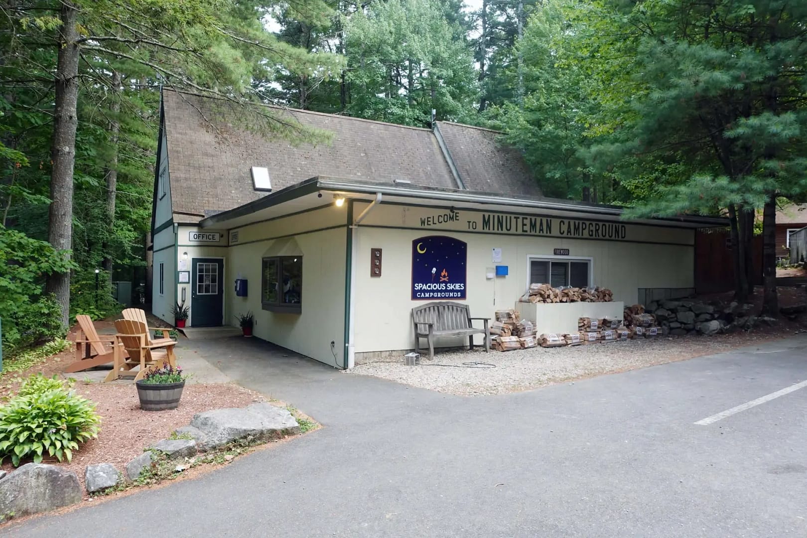 A small art gallery in the woods with a bench and chairs.