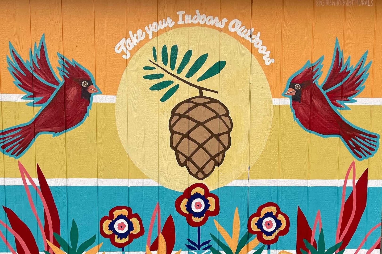 A colorful painted wall with blooming birds and pine cones.