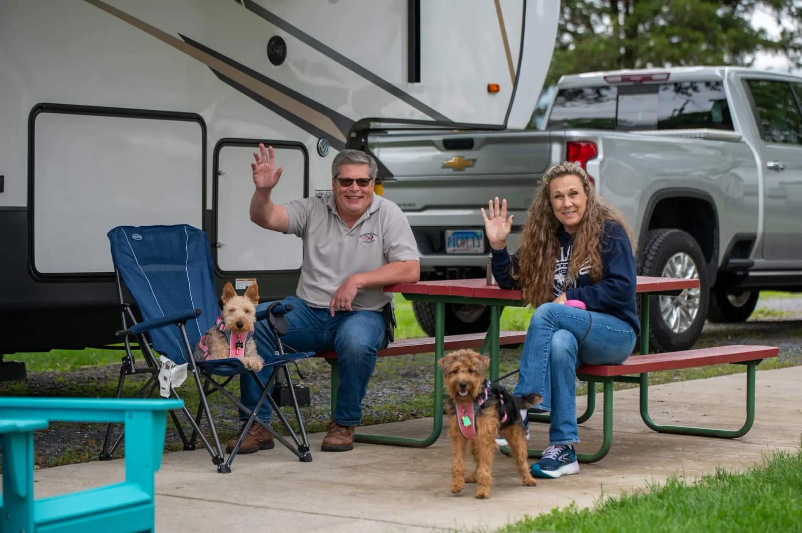 A couple with their dogs siting on patio near a parked RV