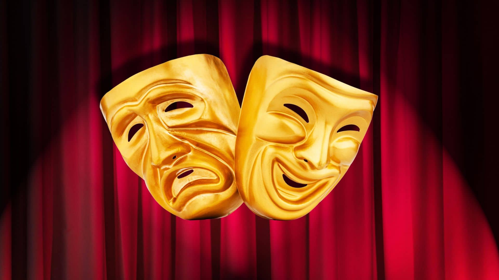 Two yellow theatrical masks representing comedy and tragedy are suspended in front of a rich red curtain, capturing the essence of the performing arts. The comedy mask smiles while the tragedy mask frowns, symbolizing the dual nature celebrated at every Savannah festival.