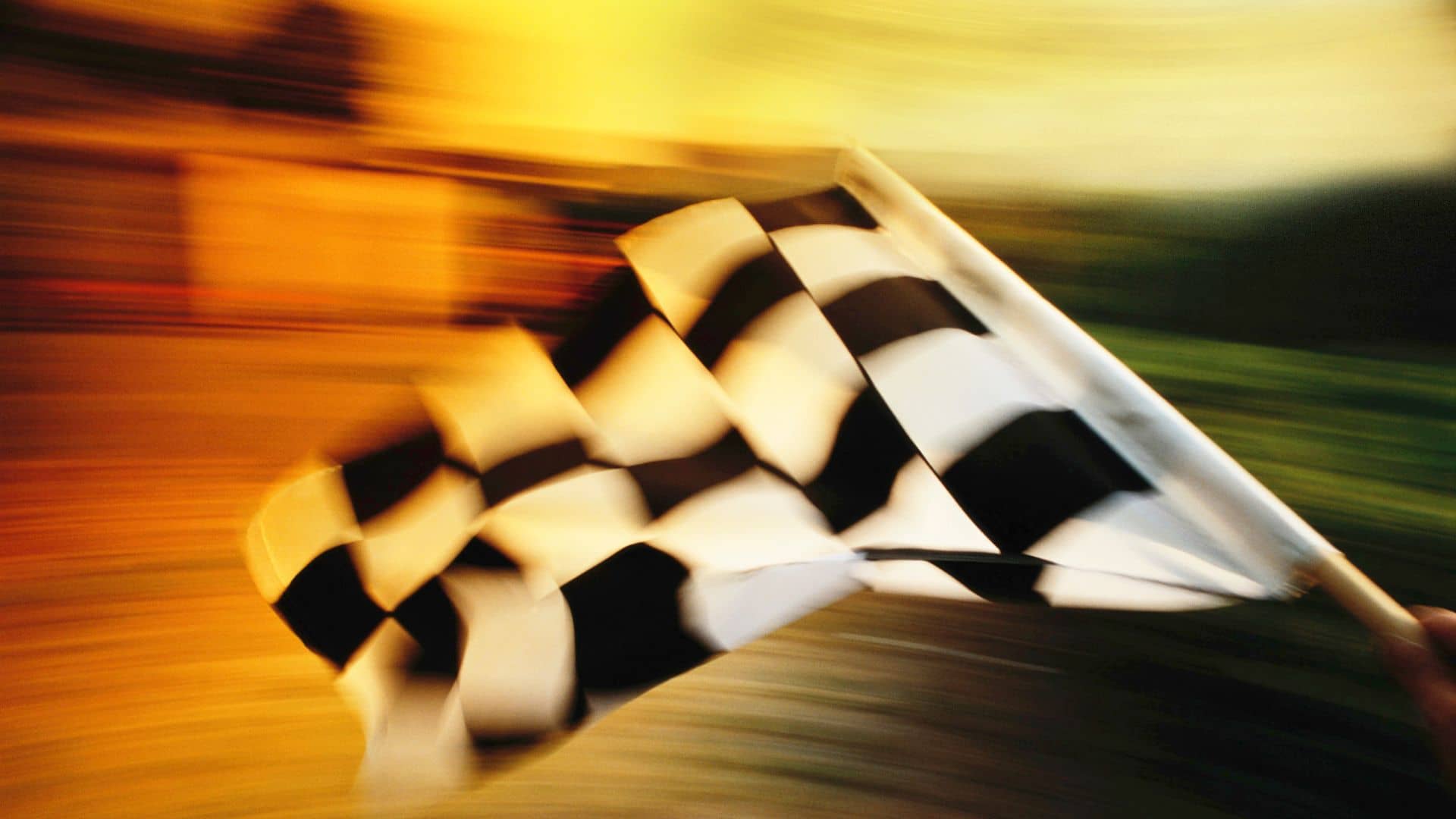 A black and white checkered flag waves in motion against a blurred, warm-colored background, capturing the thrill for race lovers and symbolizing movement or the end of a race.