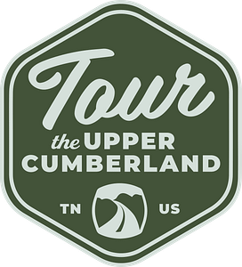 A hexagonal green logo with white text reading "Tour the Upper Cumberland" features "TN" and "US" on either side of a stylized mountain and road icon at the bottom, highlighting various activities in the region.