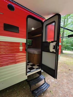A red and white rv with a bed and a black and white checkered floor.