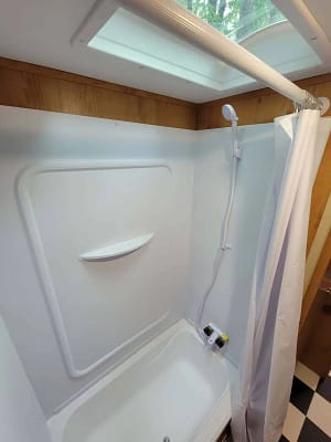 A shower with a shower head and shower curtain.