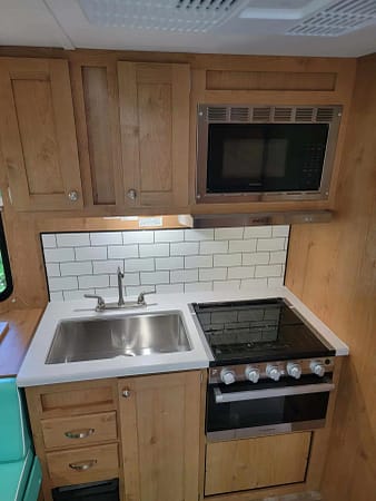 A kitchen in a small rv with a stove and sink.
