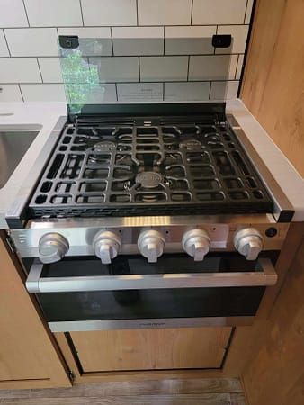A stove with a grill and a sink.
