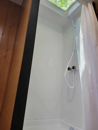 A shower with a shower curtain and a hose.