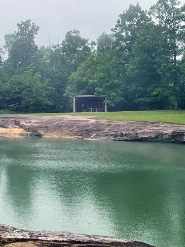 A lake with a shelter and trees.