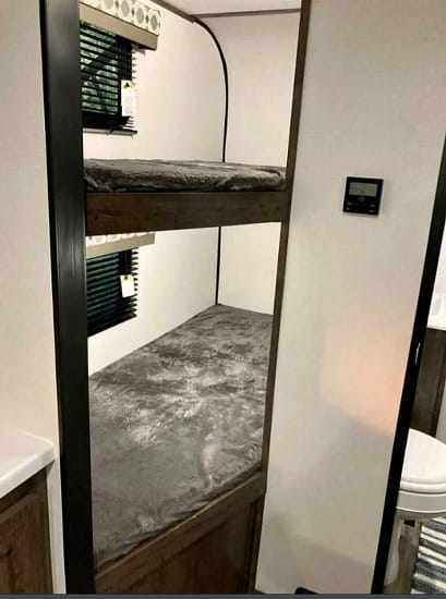 An RV interior with a bed and sink, perfect for camping.