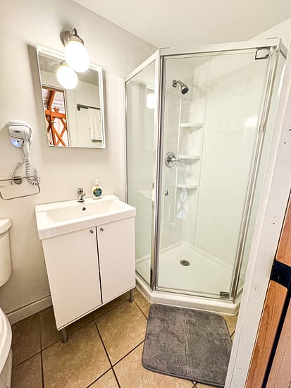 Small modern bathroom with a glass shower enclosure and white vanity.