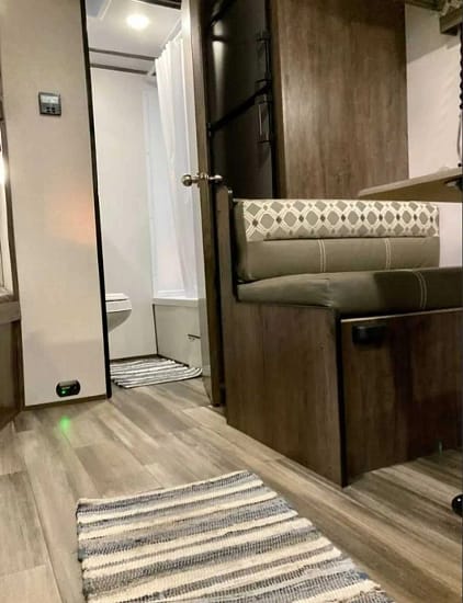 The interior of a small RV with a bed and sink, perfect for camping.