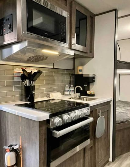 A kitchen in a small RV with a stove and microwave.