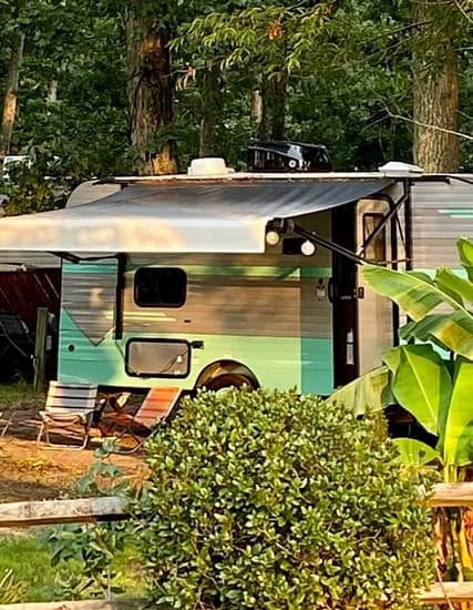 An RV parked in a wooded area for camping.