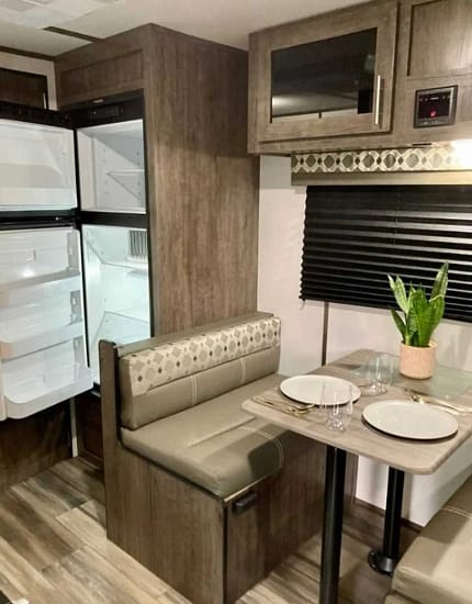 The interior of an RV with a refrigerator and a table is the perfect space for camping trips.