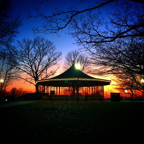A gazebo in a park during sunset.