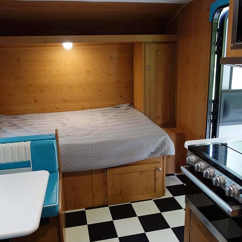 A bed and stove in a camper.