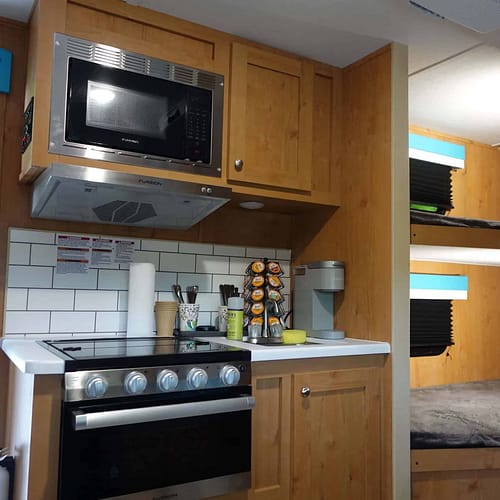 A kitchen with a microwave oven and a bunk bed.