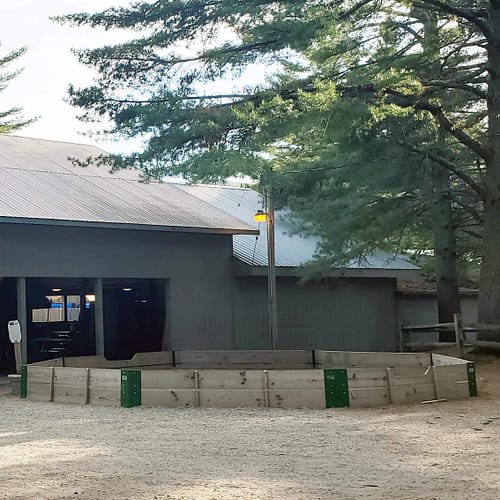 A building with a round fence and a large tree.