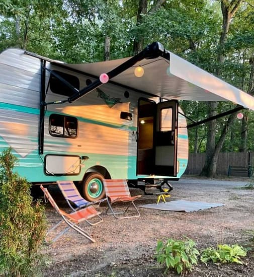An RV is parked in a wooded area, providing a serene camping experience.