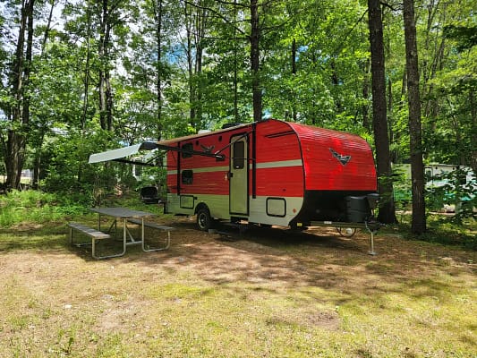 A red and silver trailer in a forest.