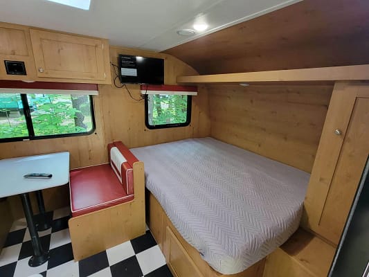 An airstream rv with a bed and a checkered floor.