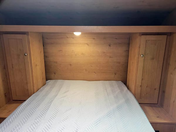 A bed with a light on the wall.