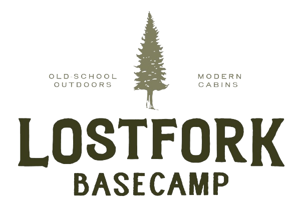 Logo for Lost Fork Basecamp featuring a tall tree in the center, with the phrases "Old-School Outdoors" on the left and "Modern Cabins" on the right. The words "LOSTFORK BASECAMP" appear prominently below.
