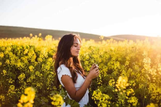 A woman in a field of blooming yellow flowers.
