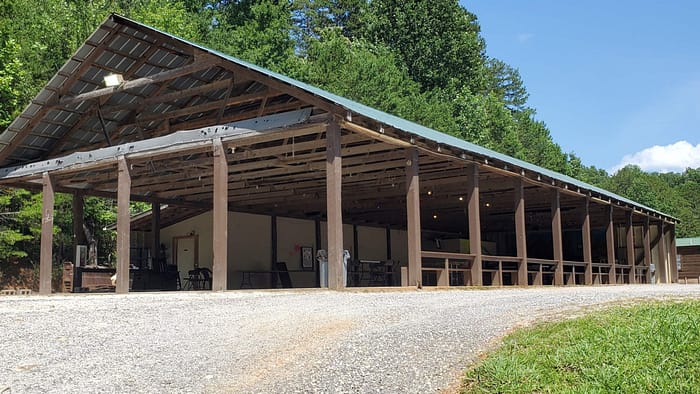 A barn in the woods with a metal roof.