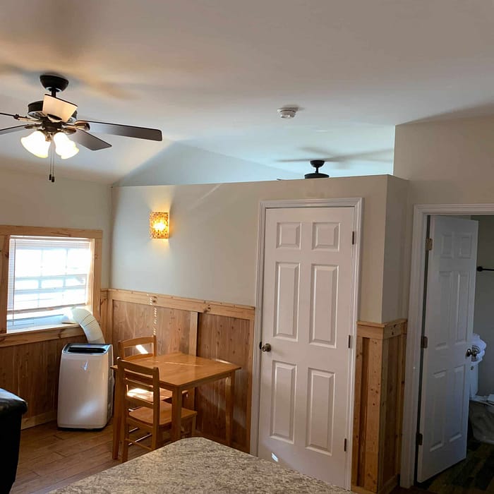 A room with a table and chairs and a fan.