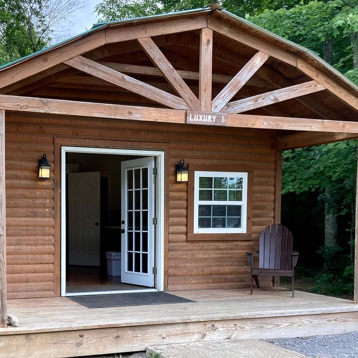 A wooden cabin with a porch and a chair.