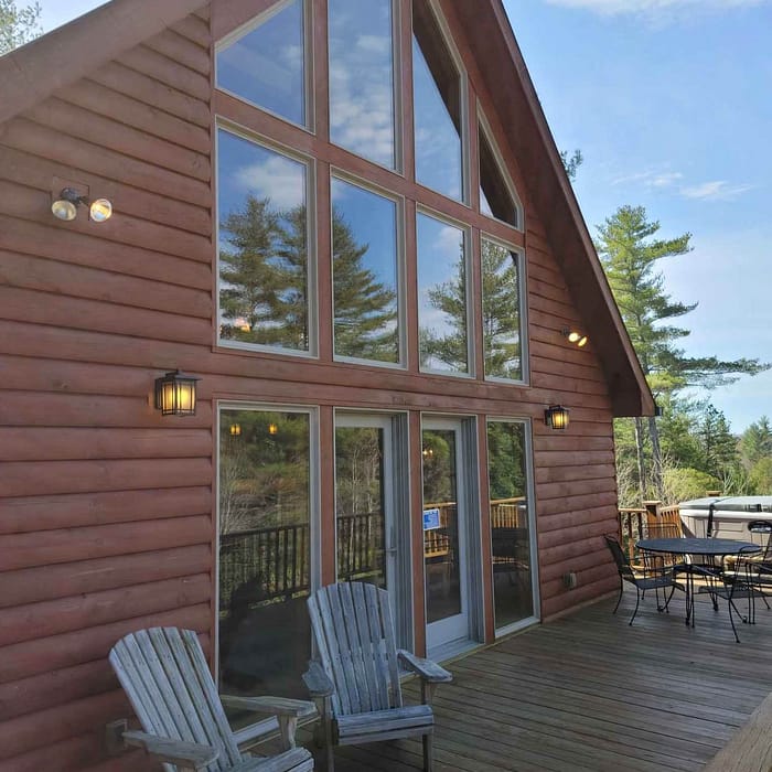 A wooden house with a deck and chairs.