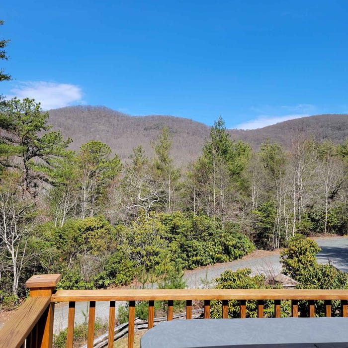 A deck with a table and a view of trees and mountains.