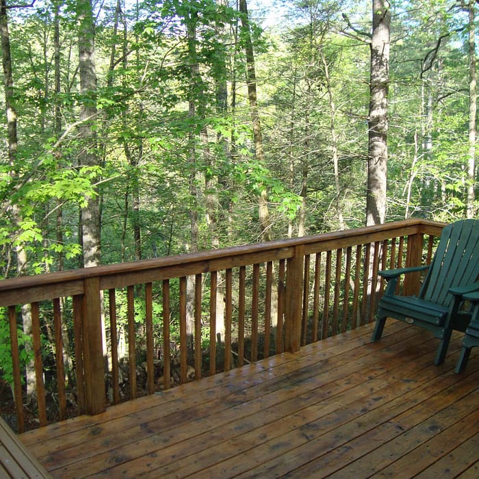 A deck with chairs and trees in the background.