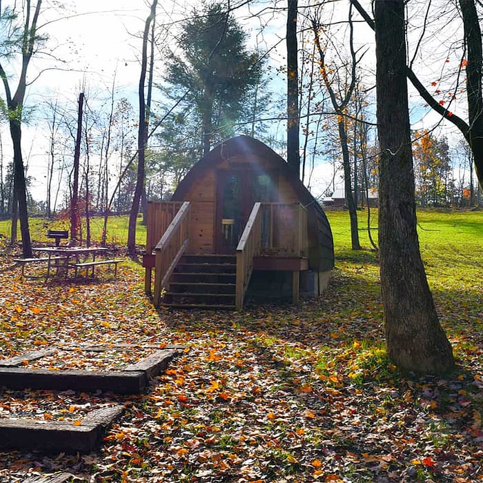 A small cabin in the woods with a picnic table.