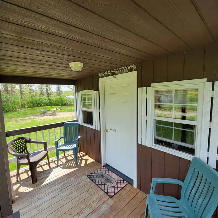 A porch with chairs and a door.
