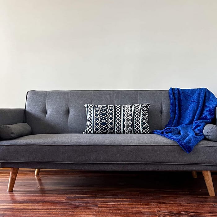 A couch with a blue blanket on it.