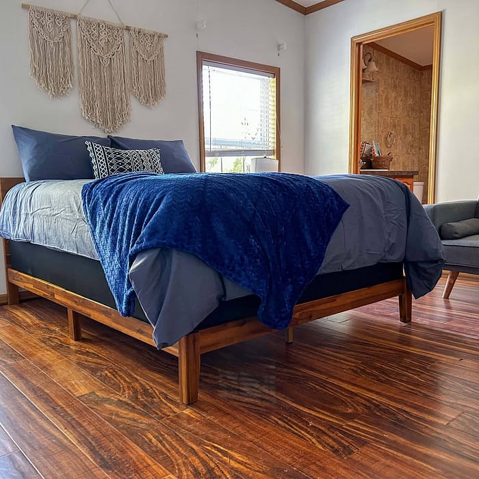 A bed with blue blankets and a wood floor.