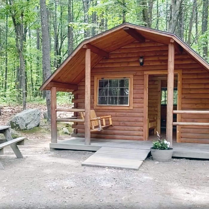 A small cabin in the woods with a picnic table, ideal for an art retreat.