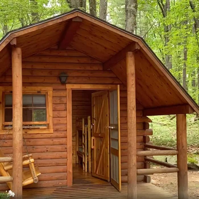 A small log cabin nestled in the woods, perfect for camping.