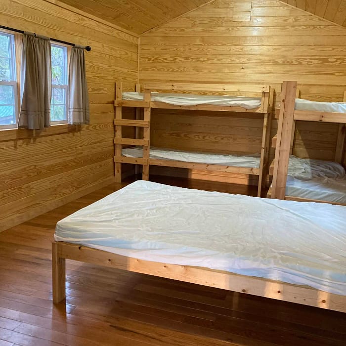 A wooden cabin interior with a double bed and a set of bunk beds.
