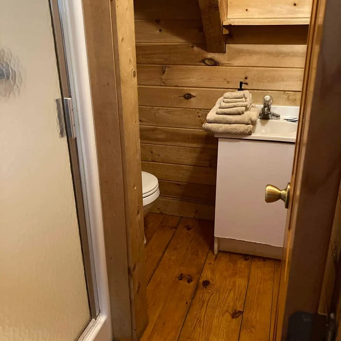Small bathroom under stairs with wooden paneling and a white sink cabinet.