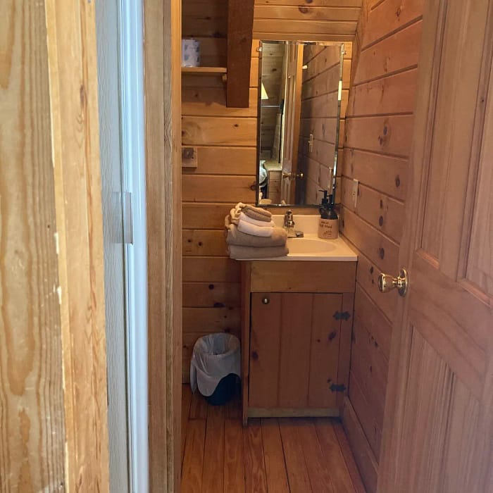 Narrow bathroom interior with wooden walls and a single vanity.