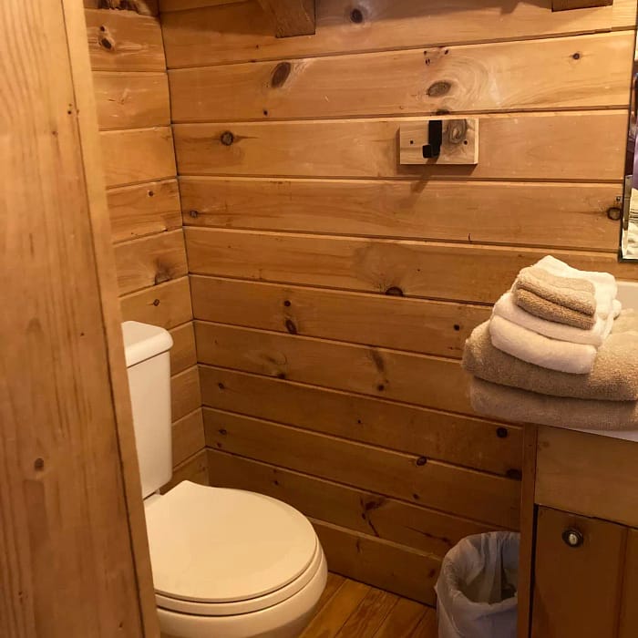 A rustic wooden bathroom interior with a toilet and towels.