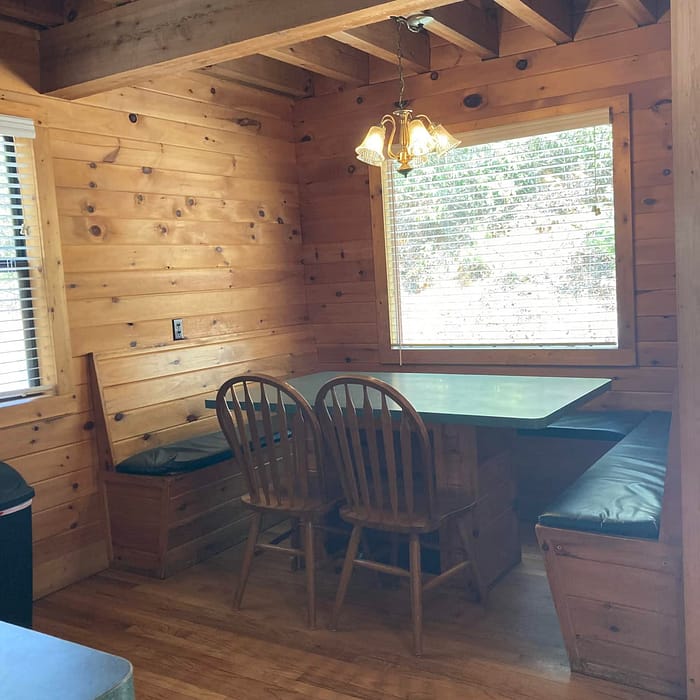 Wood-paneled dining area with bench seating, a table, chairs, and a hanging light fixture.