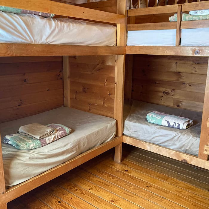 Wooden bunk beds with bedding in a cabin room.