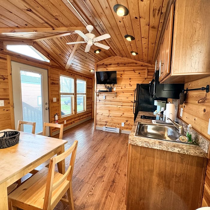 Interior of a cozy, wooden cabin kitchen with modern appliances and a dining area.